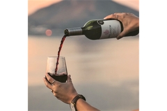 Pouring wine into a glass in front of a mountain.